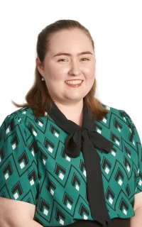 Woman in patterned business shirt, smiling. 